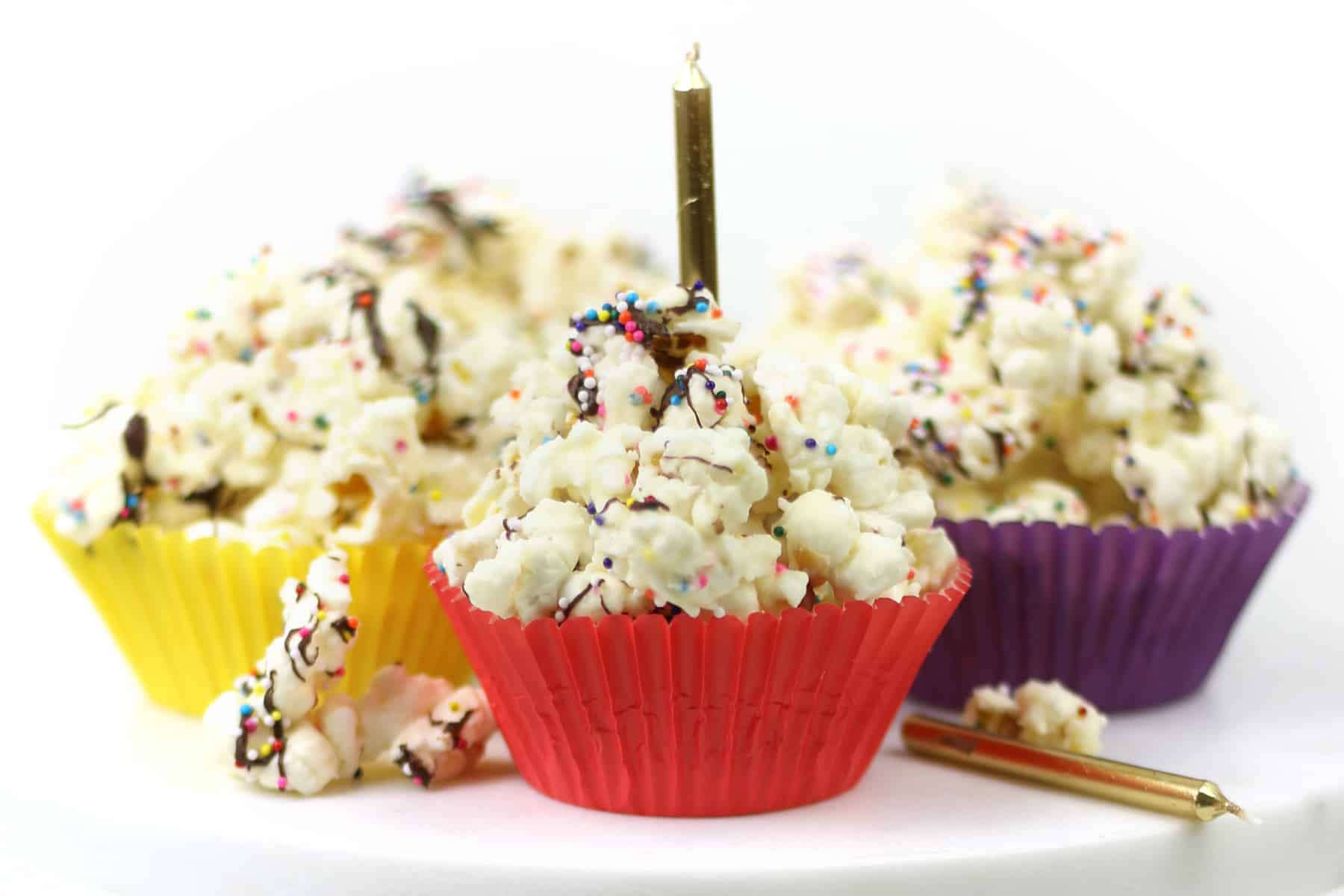 Birthday cake popcorn with sprinkles scooped into cupcake wrappers.