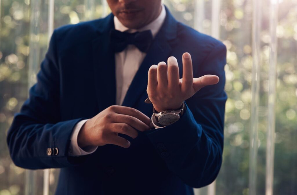 Man in dark suit adjusting cufflinks.