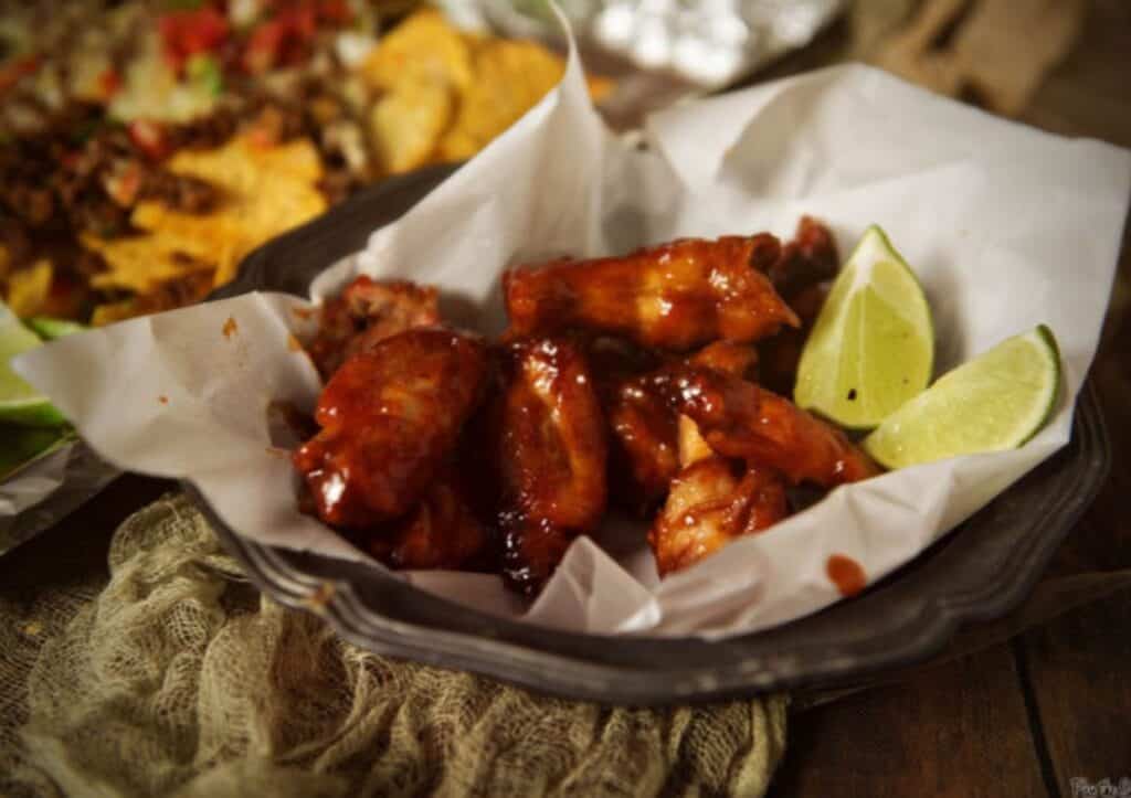 Wings on a platter with lime wedges.