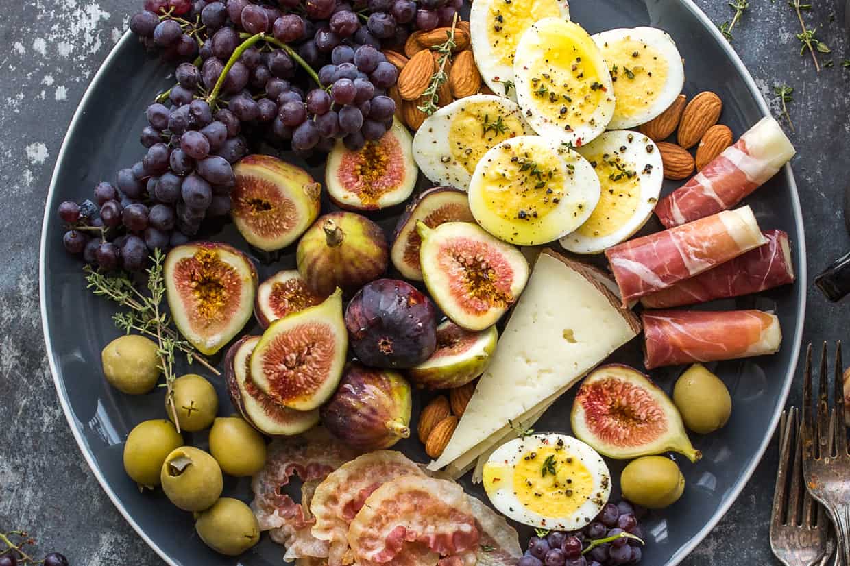 A plate of fruits, meats and cheeses.
