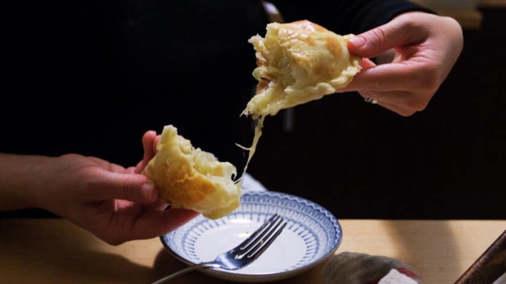 Hands ripping apart an Argentinian empanada.