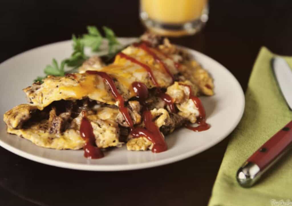 Omelet filled with beef and topped with ketchup.