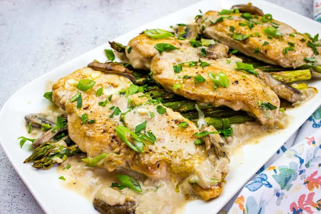 Chicken Marsala with asparagus on a white plate.