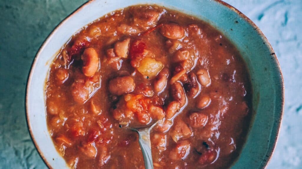 A light green ceramic bowl filled with a chunky red chili.