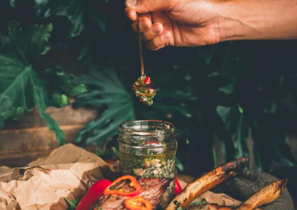 Hand spooning out chimichurri.