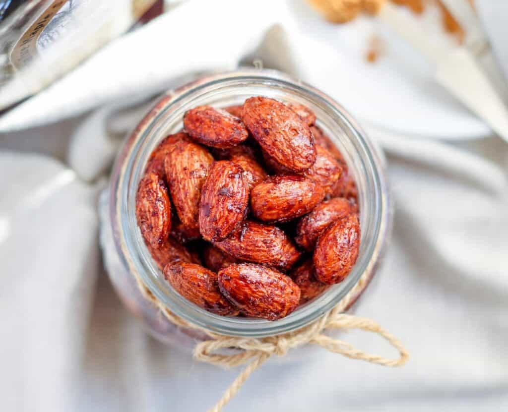 Overhead image of cinnamon almonds in a jar.