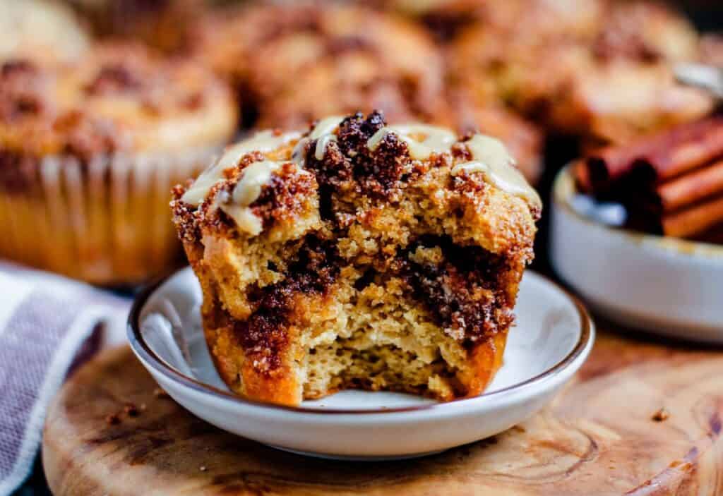 Cinnamon roll muffin on a small plate with a bite out of it.