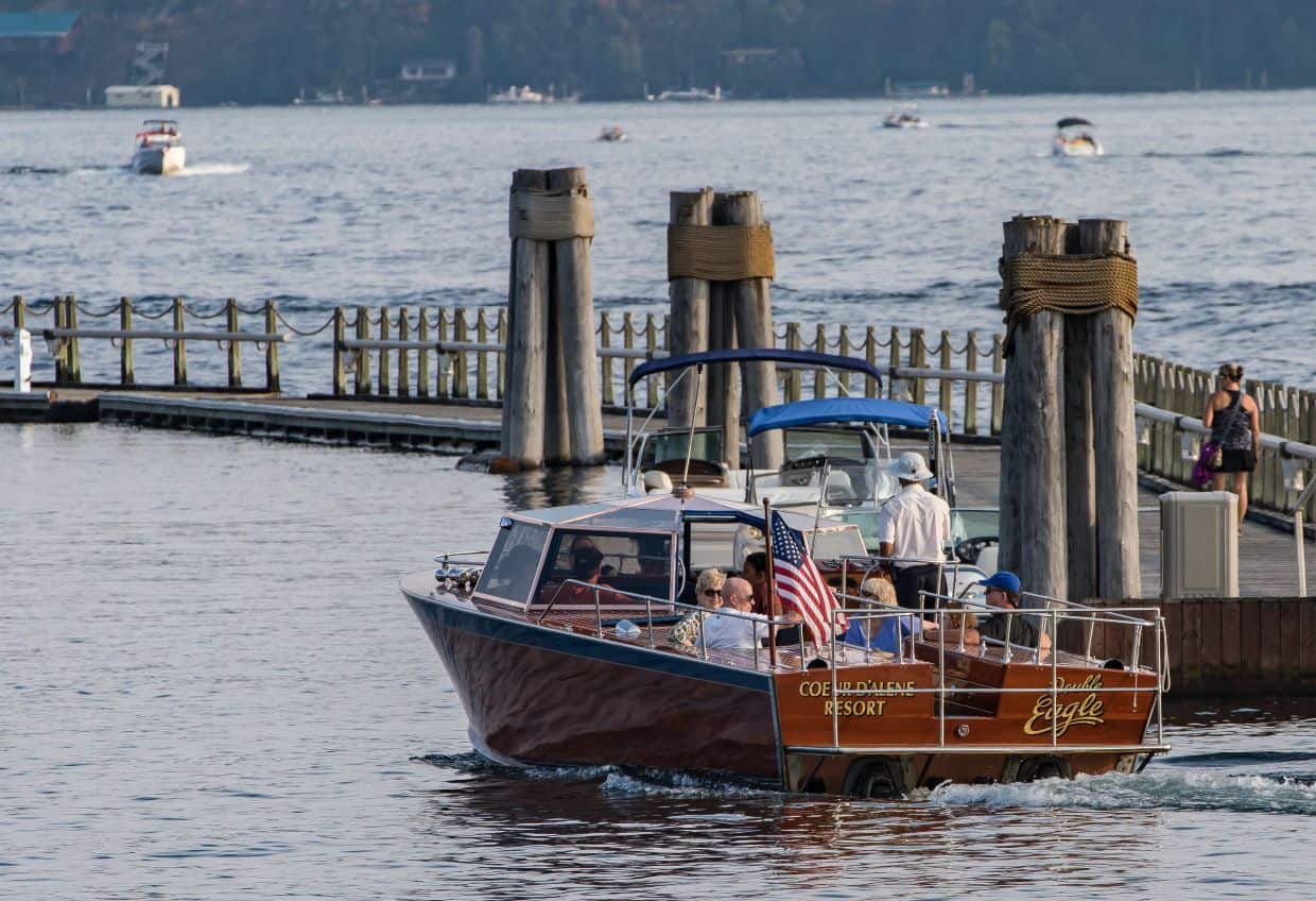 Passenger boat on mountain lake next to boardwalk.