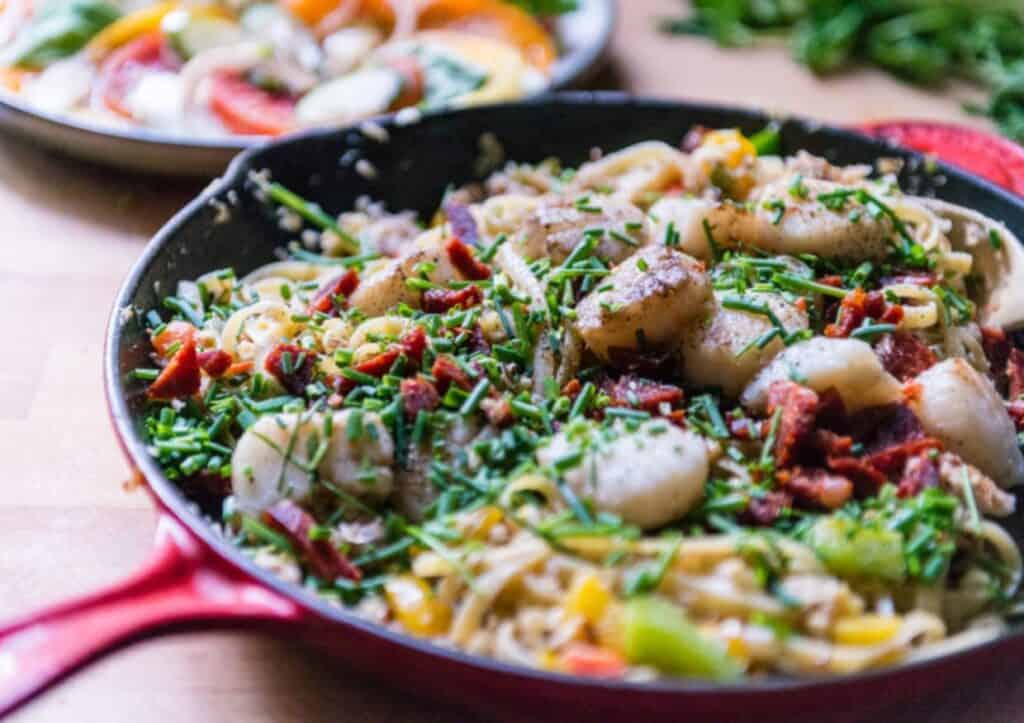 Scallops and crab meat in a colorful skillet.