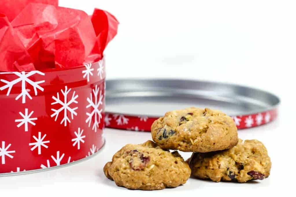 A stack of cranberry cookies next to a red cookie tin with snowflakes.