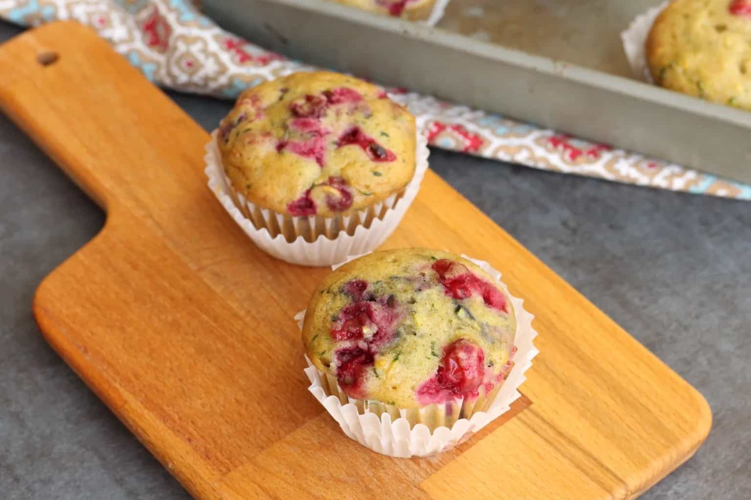Two muffins on a small cutting board.