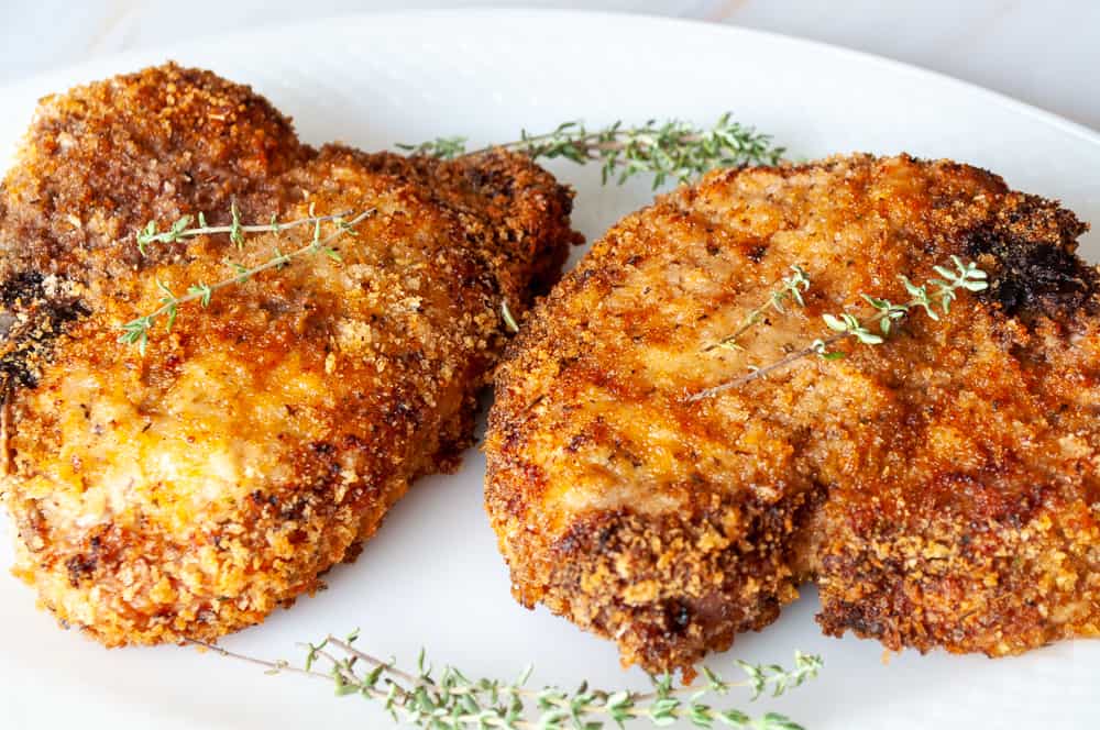 Crispy pork chops on a platter with thyme. 