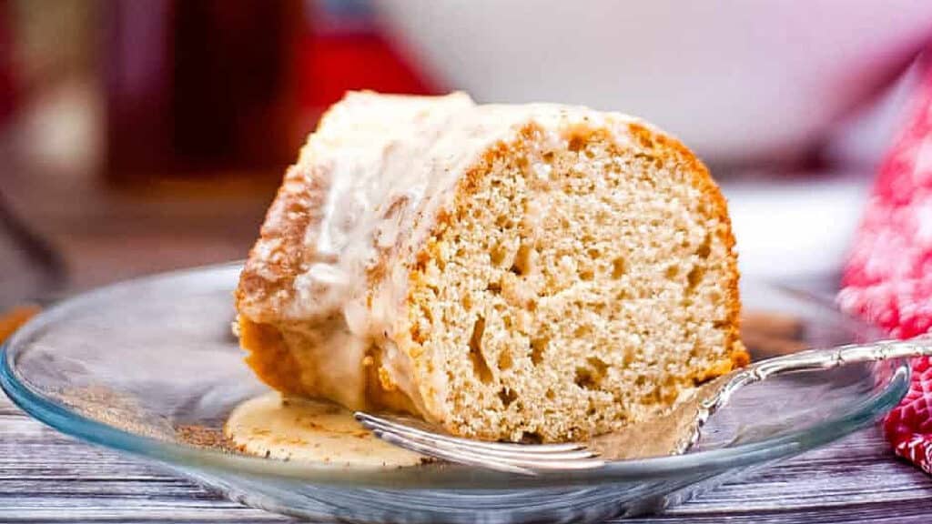 Eggnog bundt cake slice on a clear glass plate with a fork.