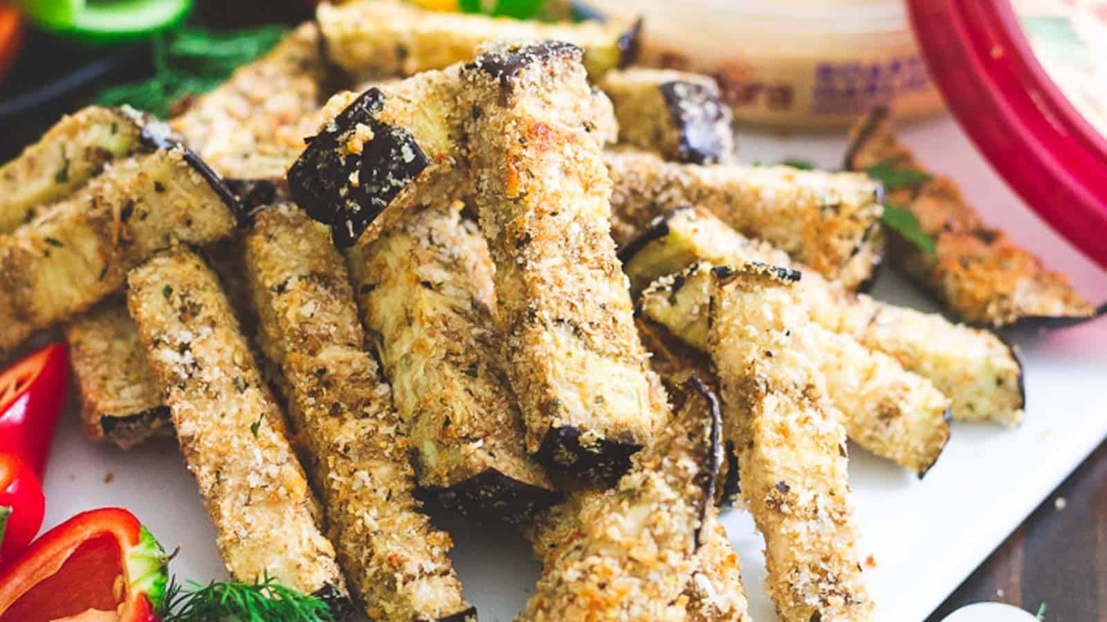 Eggplant fries on a white plate with hummus as a dip.