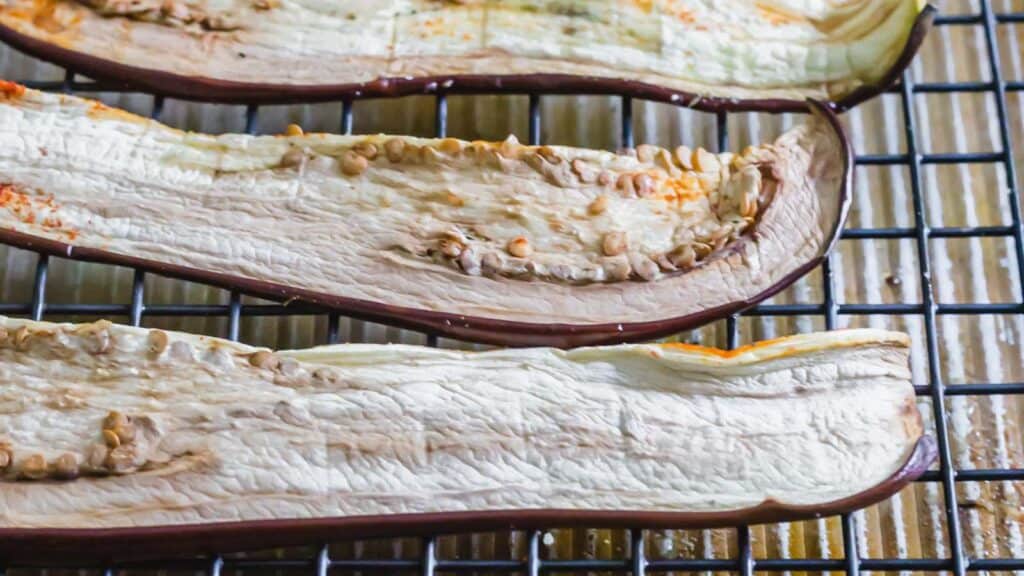 Eggplant jerky with seasonings on a wire rack.