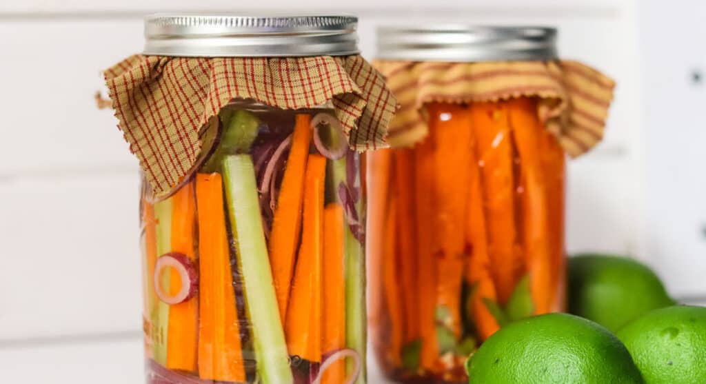 Fermented carrots and celery in glass mason jars with limes.