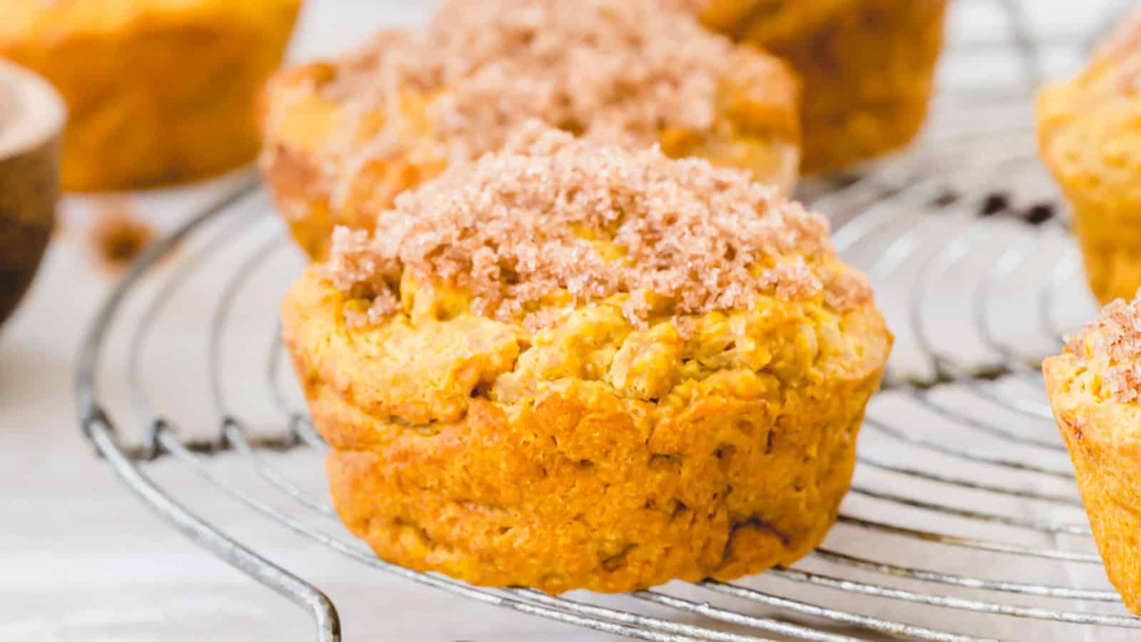 Gluten free pumpkin muffins on a cooling rack with cinnamon sugar topping.