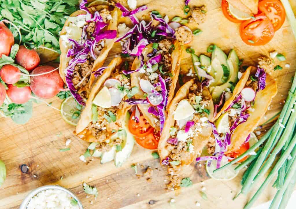Overhead image of colorful tacos and toppings.