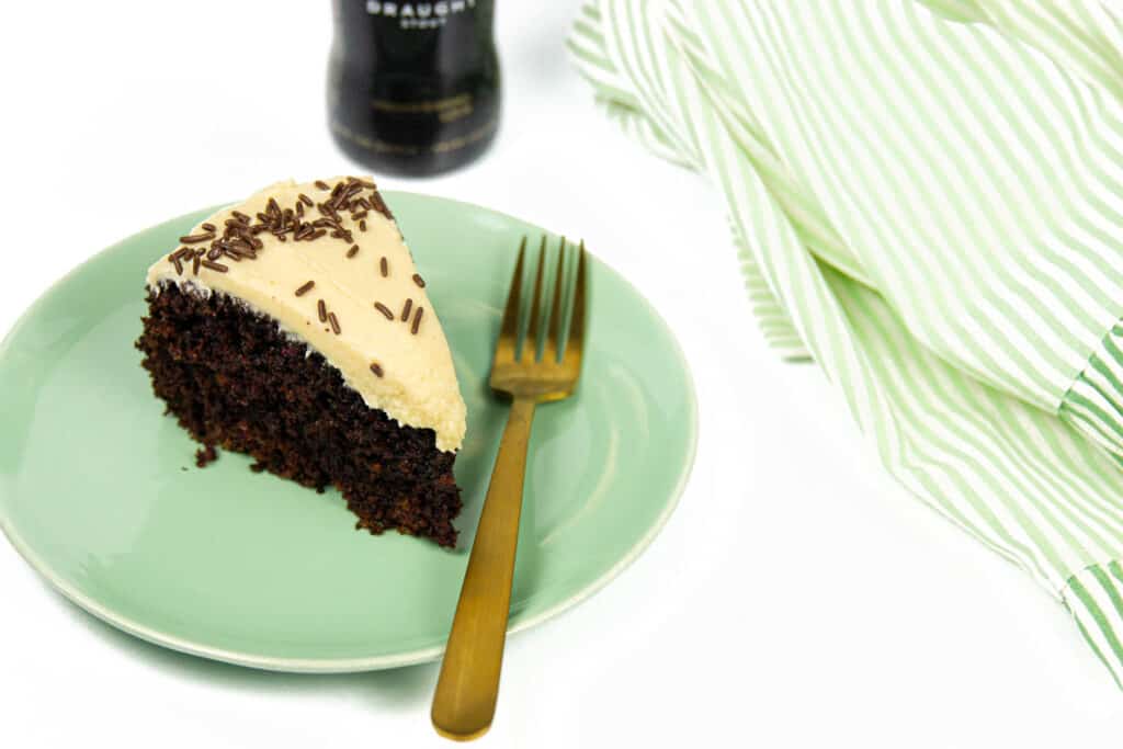 A slice of Chocolate Guinness Cake with a gold fork and a striped kitchen towel.