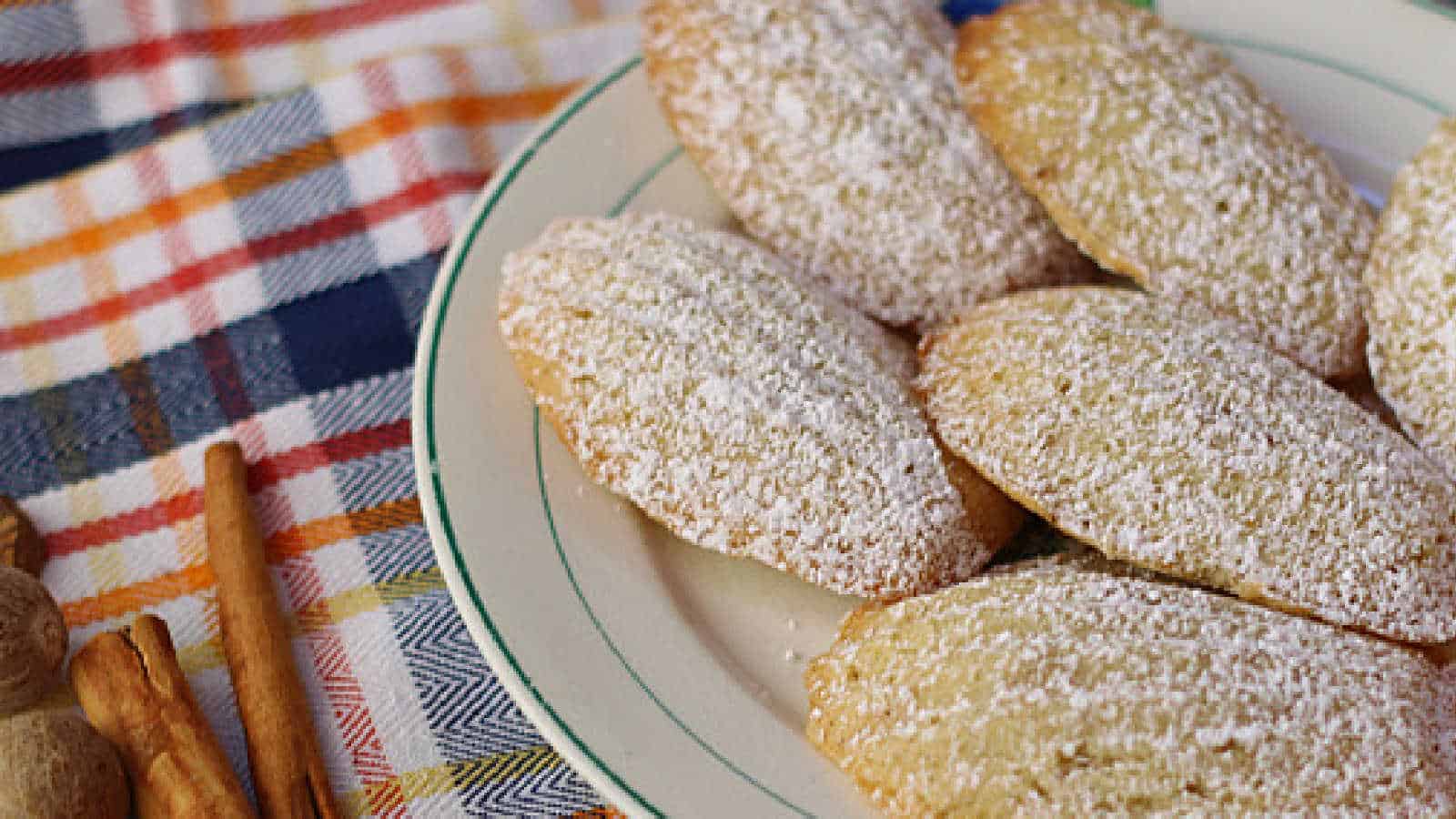 A plate with madeleine cakes sprinkles with powdered sugar.