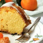 Mandarin Orange Bundt Cake slice on a white plate with slices of oranges.