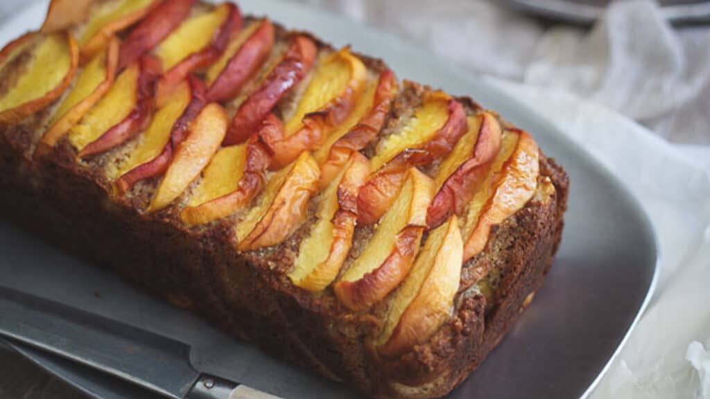 Maple peach bread on a silver plate with knife.