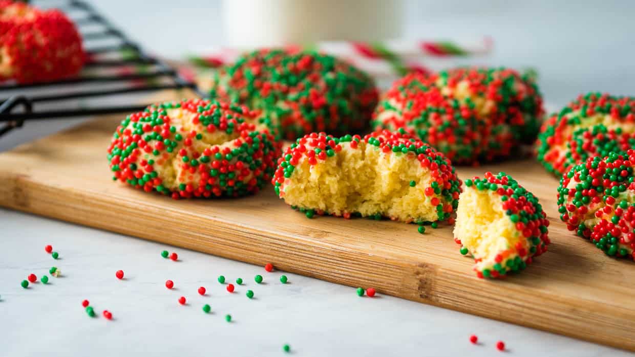 Red and green cake mix cookies on a wooden cutting board.
