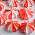 Meringue cookies decorated with red and white stripes on a cake stand.