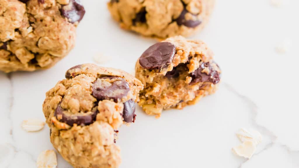 Oatmeal chocolate chip cookies on white surface split open.