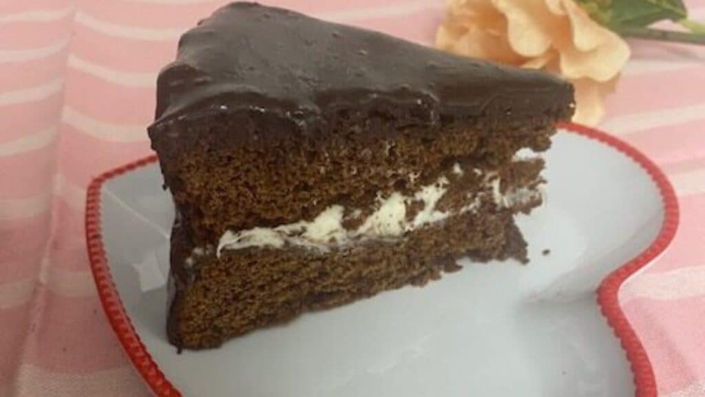 A slice of chocolate cake resting on a red and white heart-shaped plate.