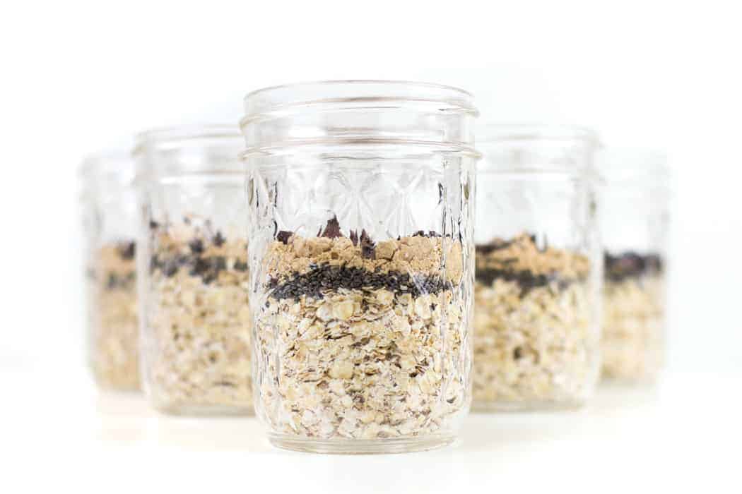 Jars of oats, chia seeds and peanut butter powder on a white background. 