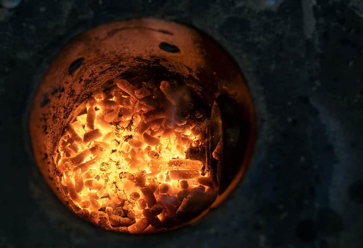 Pellets burning in a fire pot of a pellet smoker.