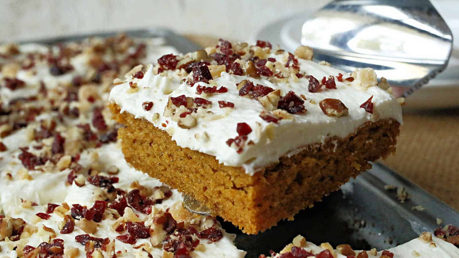 A slice of pumpkin cake with white icing.