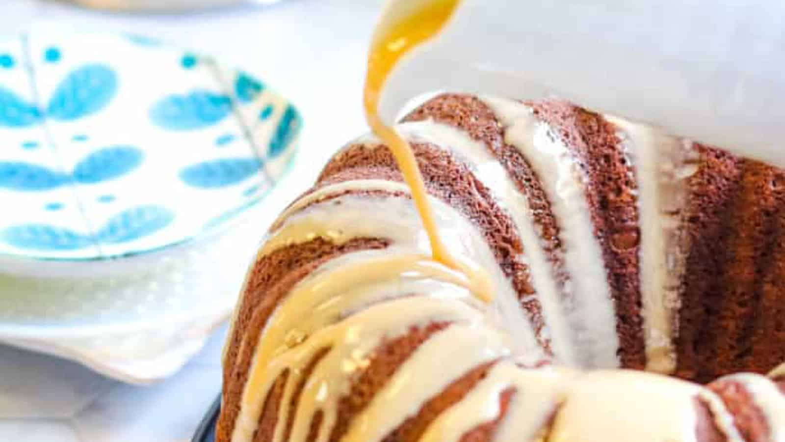 Pumpkin spice latte bundt cake with coffee glaze being poured over the top.