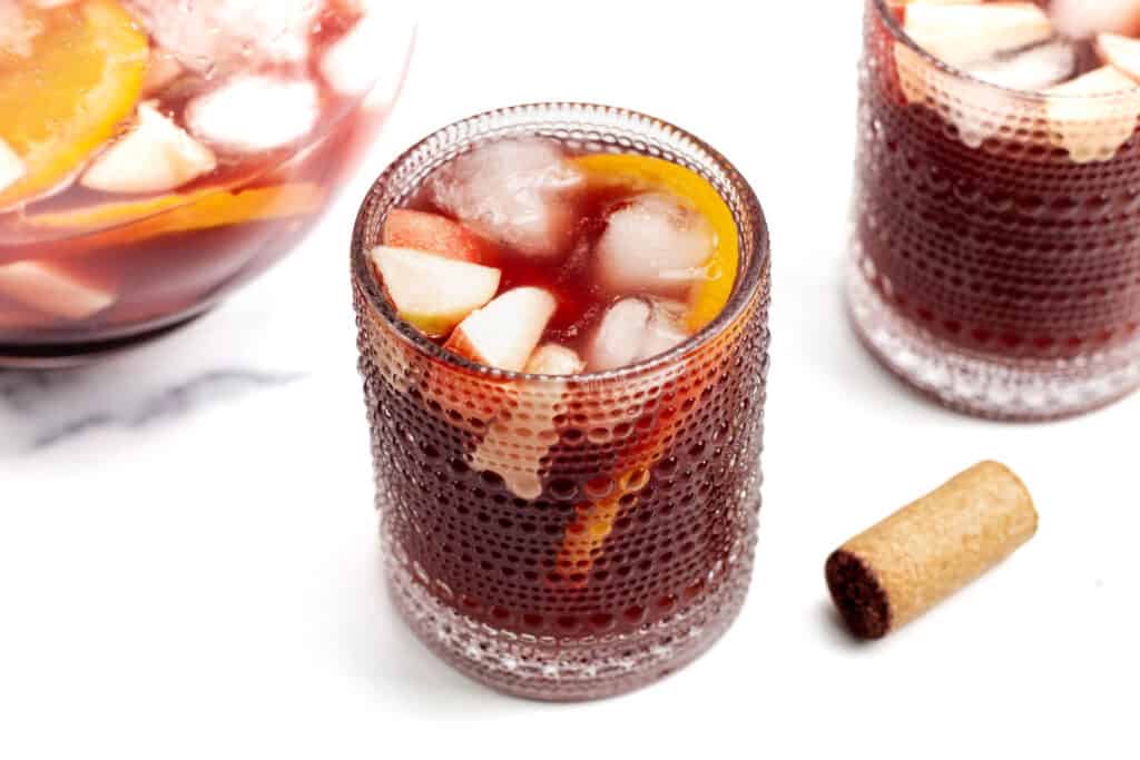 A pitcher of sangria next to two full glasses and the wine cork.