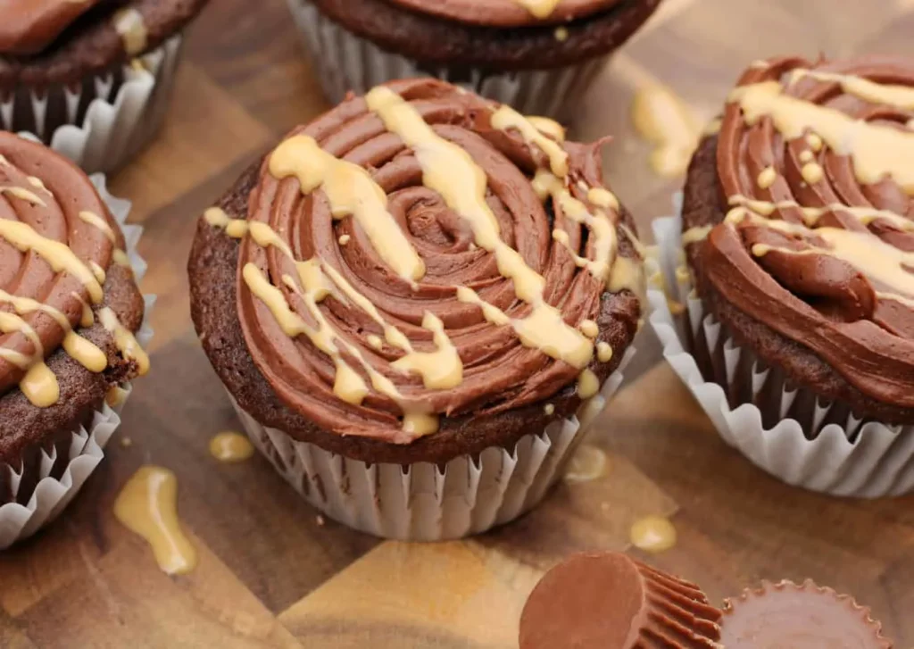 Closeup of cupcakes with chocolate icing and a peanut butter drizzle.