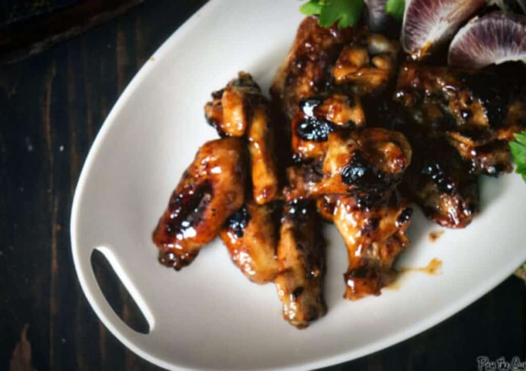 Close up of chicken wings on a white plate.