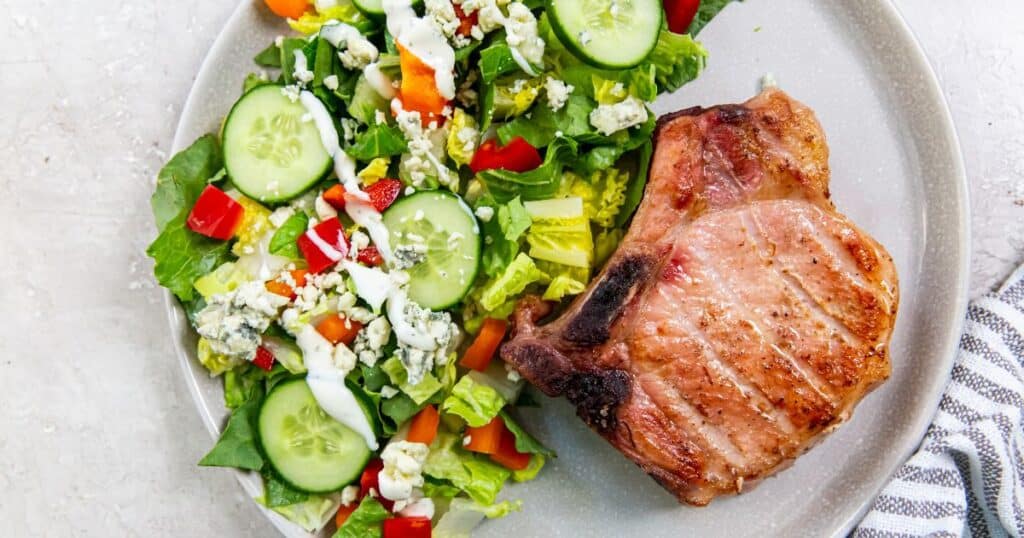 Smoked pork chops on a plate with a side salad.