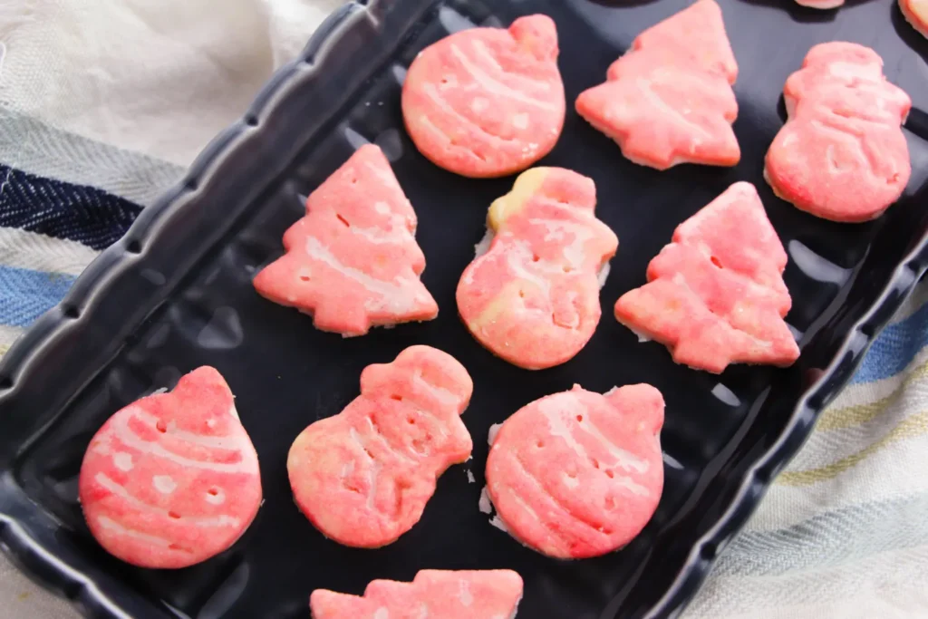 Glazed Christmas shaped sugar cookies on a black plate.