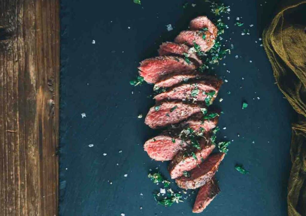 Sliced teres major steak on black board.