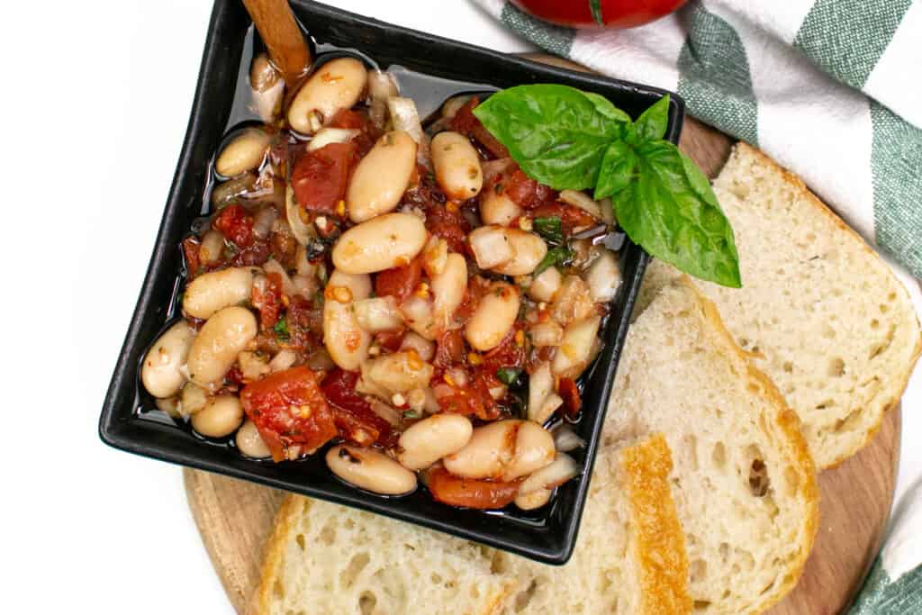 A square bowl of Tuscan White Bean Dip with bread.