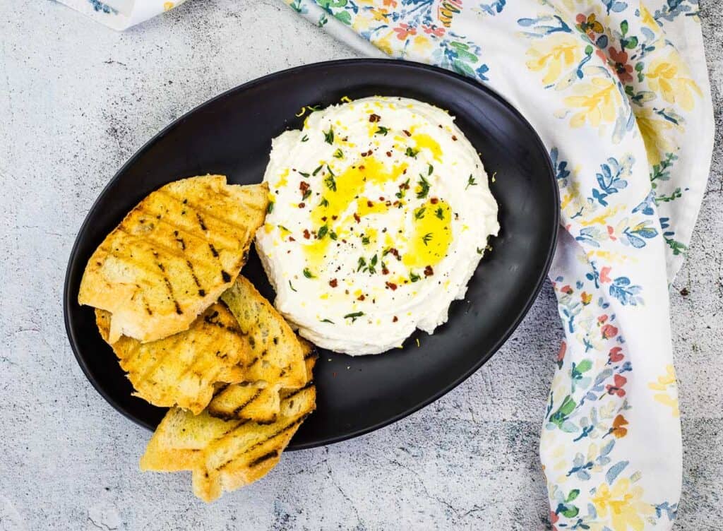 Whipped Feta on a black plate with grilled bread.