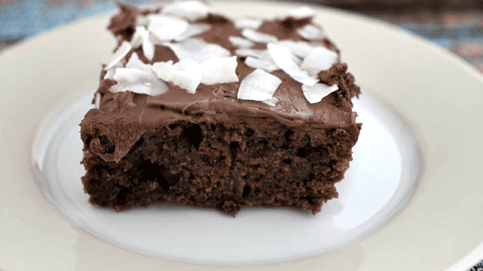 Slice of Zucchini chocolate cake with frosting and coconut.