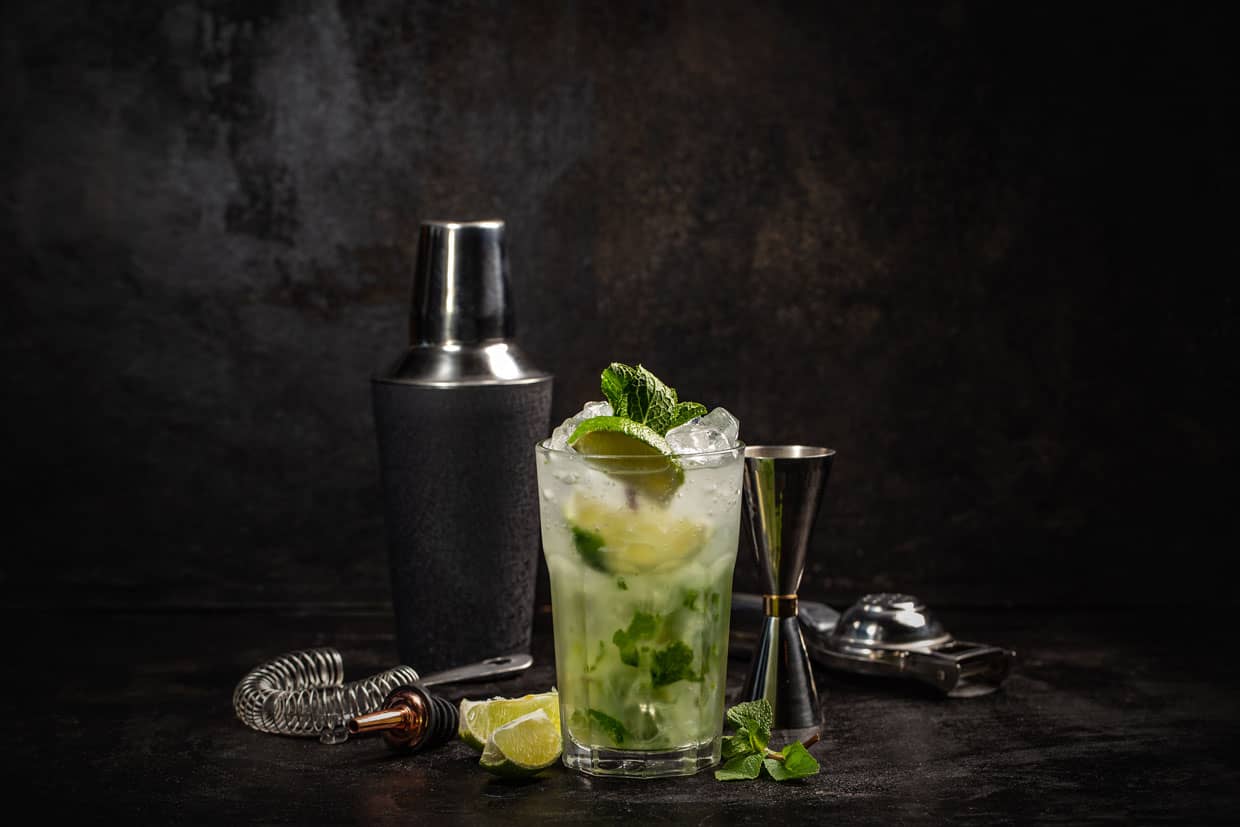 A mojito with lime and mint on a dark background.