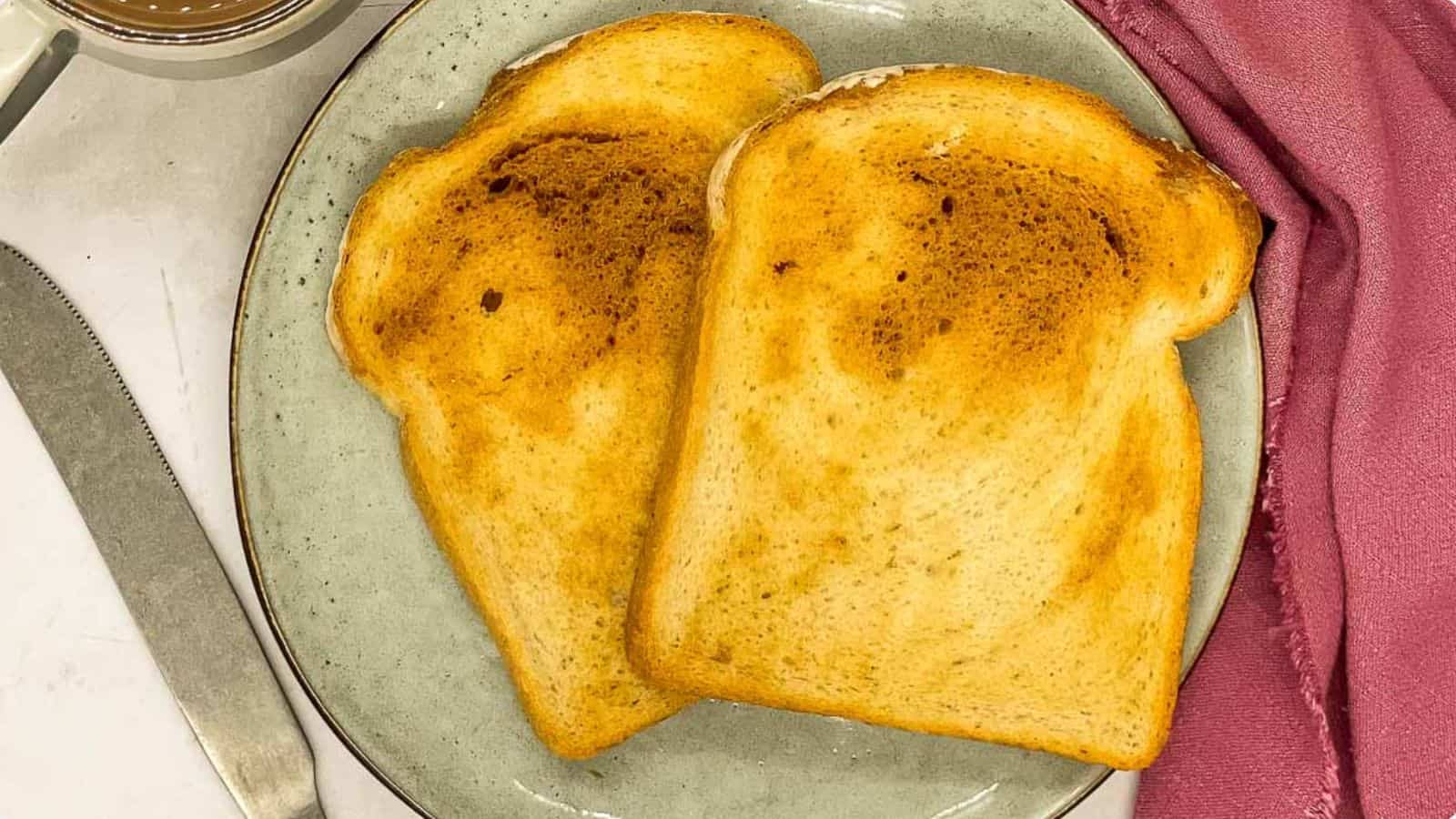 Two slices of toast on a plate with a cup of coffee.