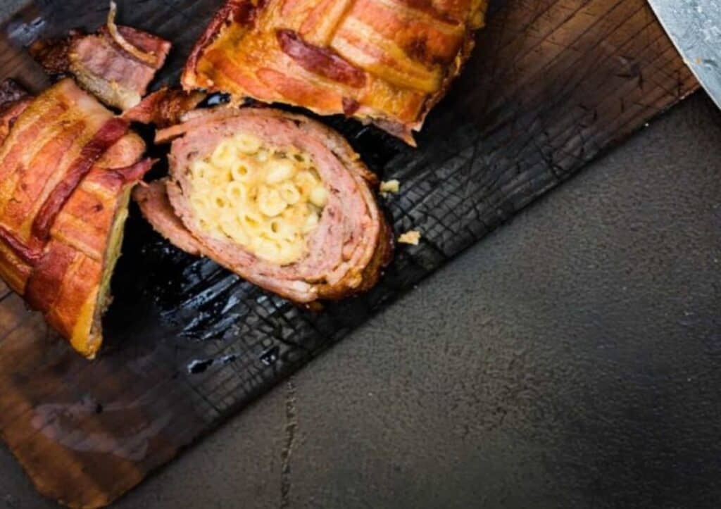 Bacon wrapped in cheese on a cutting board.