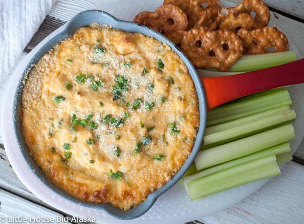 Cheesy buffalo chicken dip with celery and crackers on a plate.
