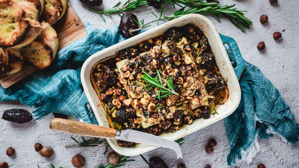 A dish with figs, nuts and bread on a blue background.