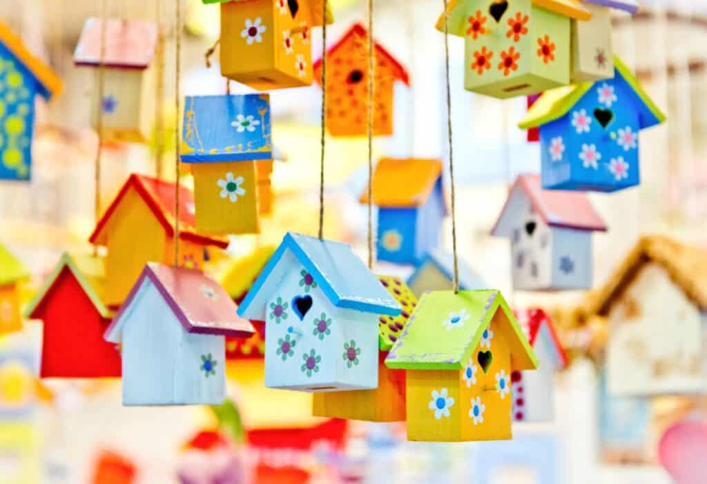 Colorful birdhouses hanging from strings in a store.