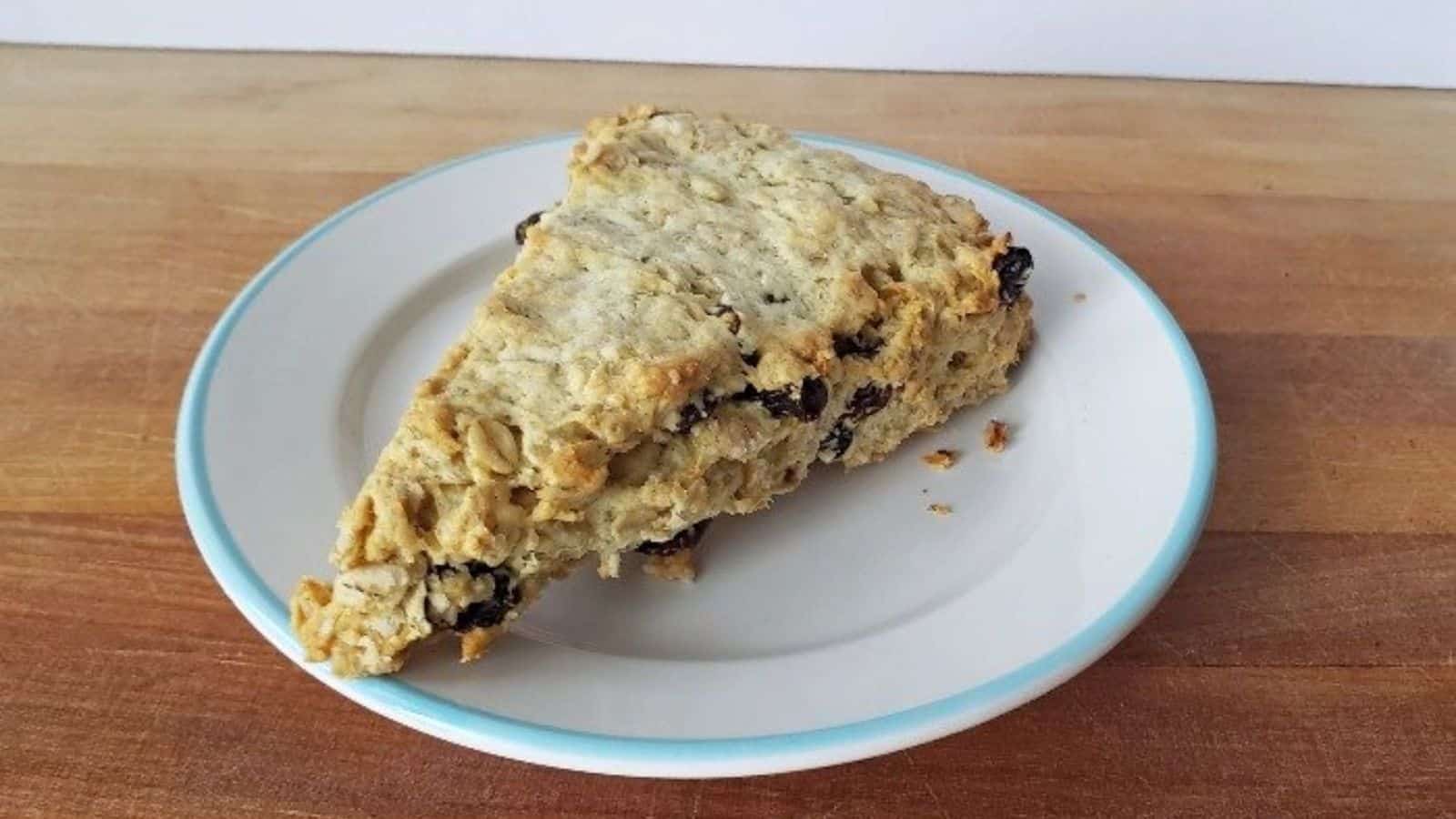 Image shows a buttermilk raisin scone on a plate.